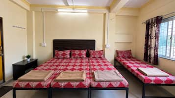 A hotel room with a large bed, two bedside tables, a ceiling fan, and a window with curtains.