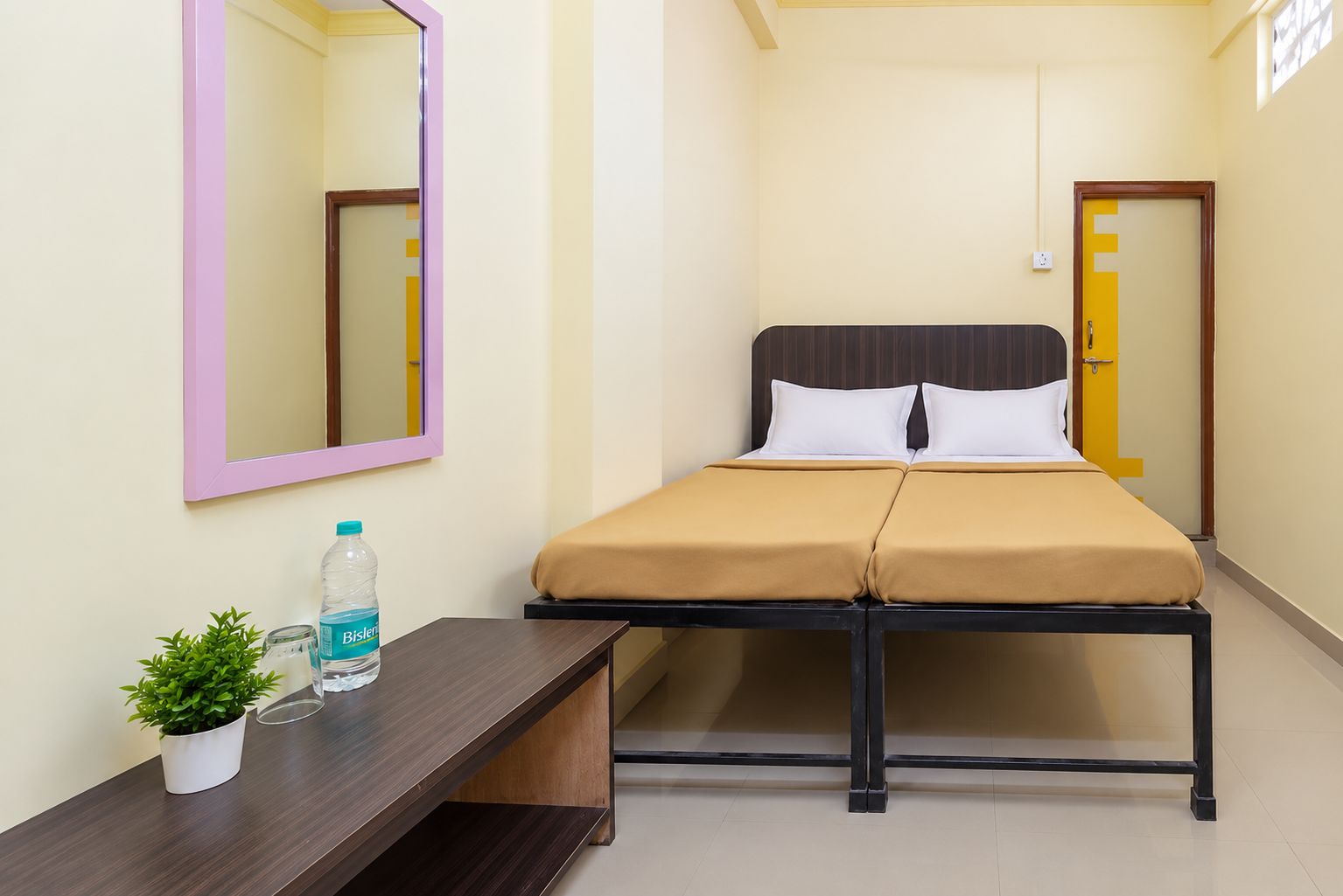 Una habitación de hotel con cama, mesita de noche y espejo.