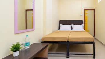 A hotel room with a bed, bedside table, and a mirror.