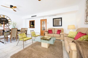 A living room with a glass coffee table, beige sofas, and a dining area with chairs and a table. - Villa INTMA Golf – Your Retreat in the Heart of Nature  (AN)