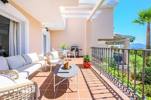 A balcony with a sofa, chairs, a table, and a grill. - Villa INTMA Golf – Your Retreat in the Heart of Nature  (AN)