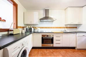 A modern kitchen with white cabinets, a Bosch oven, a washing machine, and a dishwasher. - Villa INTMA Golf – Your Retreat in the Heart of Nature  (AN)