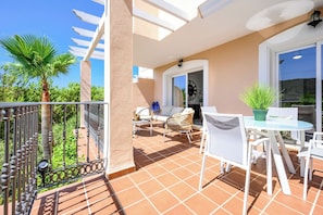 A balcony with a white table, chairs, and a potted plant. - Villa INTMA Golf – Your Retreat in the Heart of Nature  (AN)