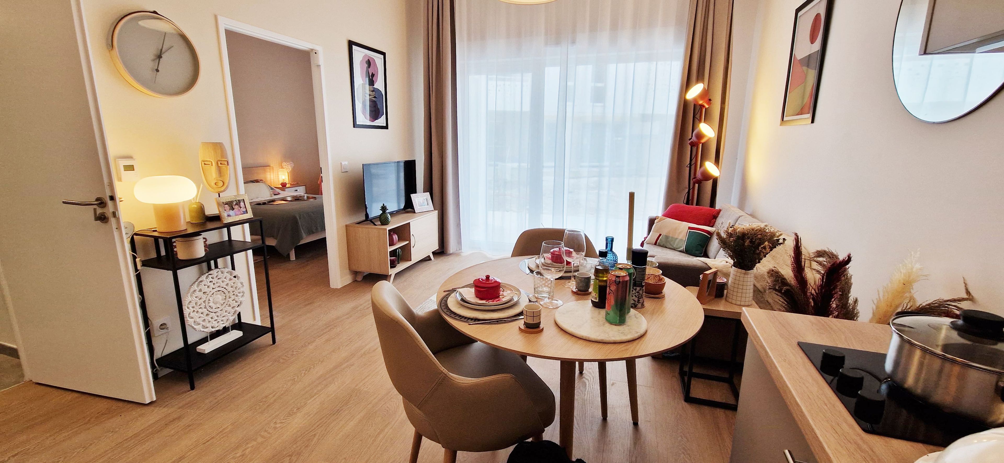 A modern hotel room with a dining area, a TV, and a bed.