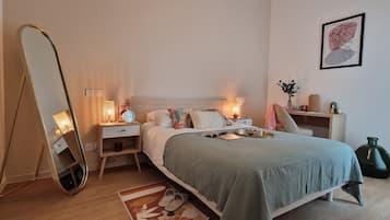 A neatly arranged bedroom with a bed, bedside tables, a mirror, a desk, and a chair.