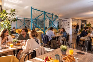 A modern cafe with tables and chairs, a blue metal structure, and a map on the wall.