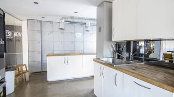 A modern kitchen with white cabinets, a wooden countertop, and stainless steel appliances.