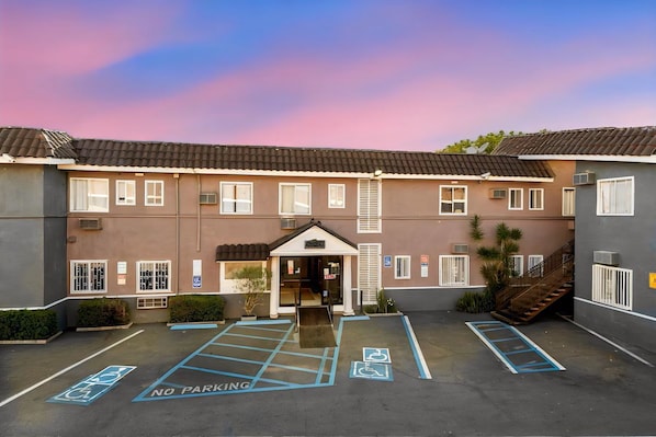 A hotel with a parking lot marked for disabled access, a no parking sign, and a building entrance.