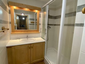 A bathroom with a wooden vanity, a sink, a mirror, and a glass-enclosed shower. - Charming apartment, exceptional location - 6 guests (Arêches-Beaufort)