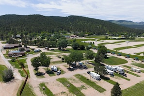 A campground with RVs, picnic tables, and a building with a green roof. - Cozy Black Hills Rustic Cabin Queen & Twin Trundle Heat AC WiFi Bathhouse Nearby (Piedmont)