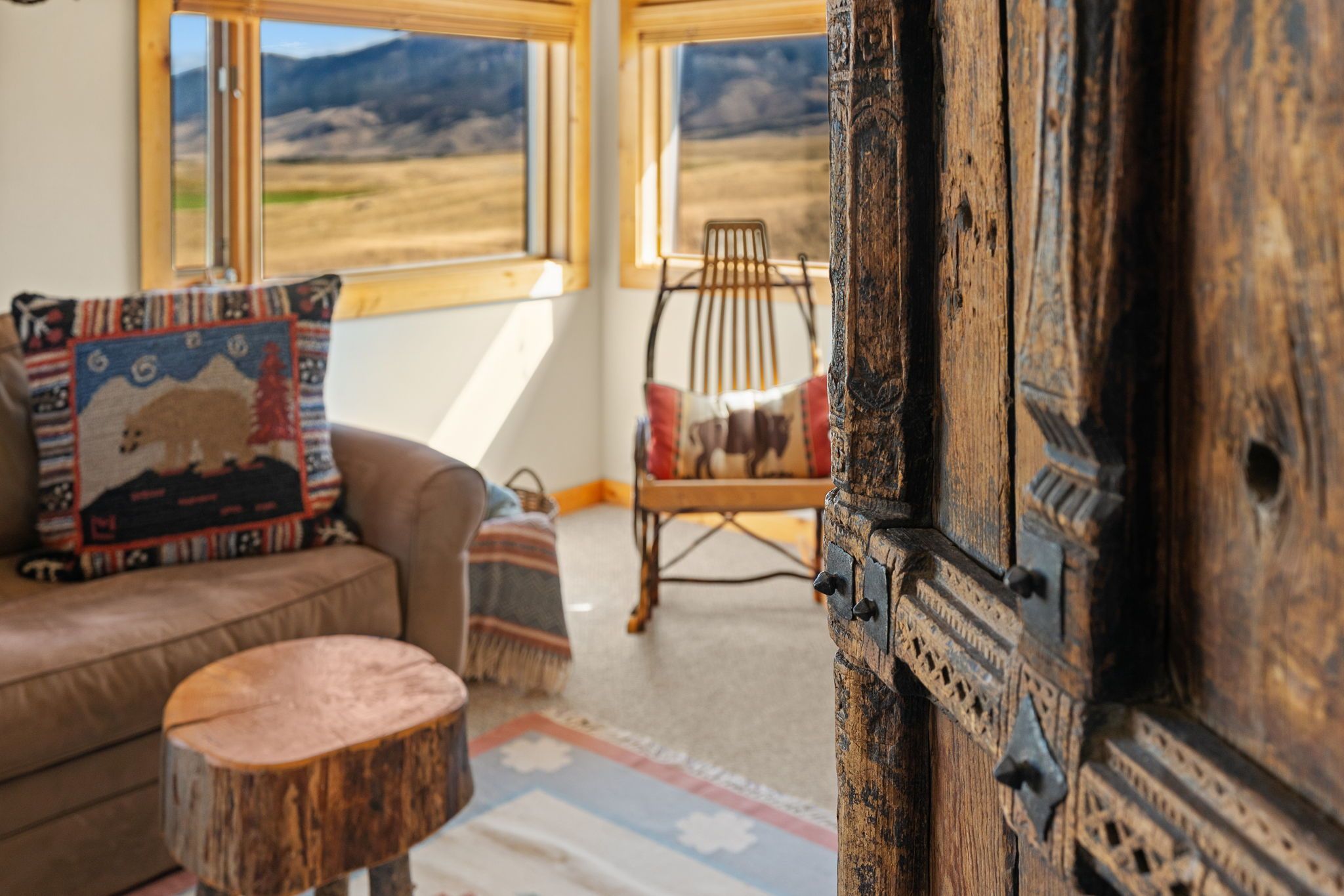 A room with a sofa, a chair, a small round table, and a large wooden door.