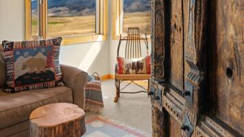 A room with a sofa, a chair, a small round table, and a large wooden door.