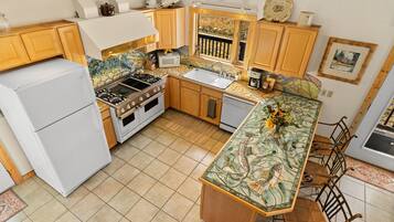 A kitchen with a stove, sink, and refrigerator.