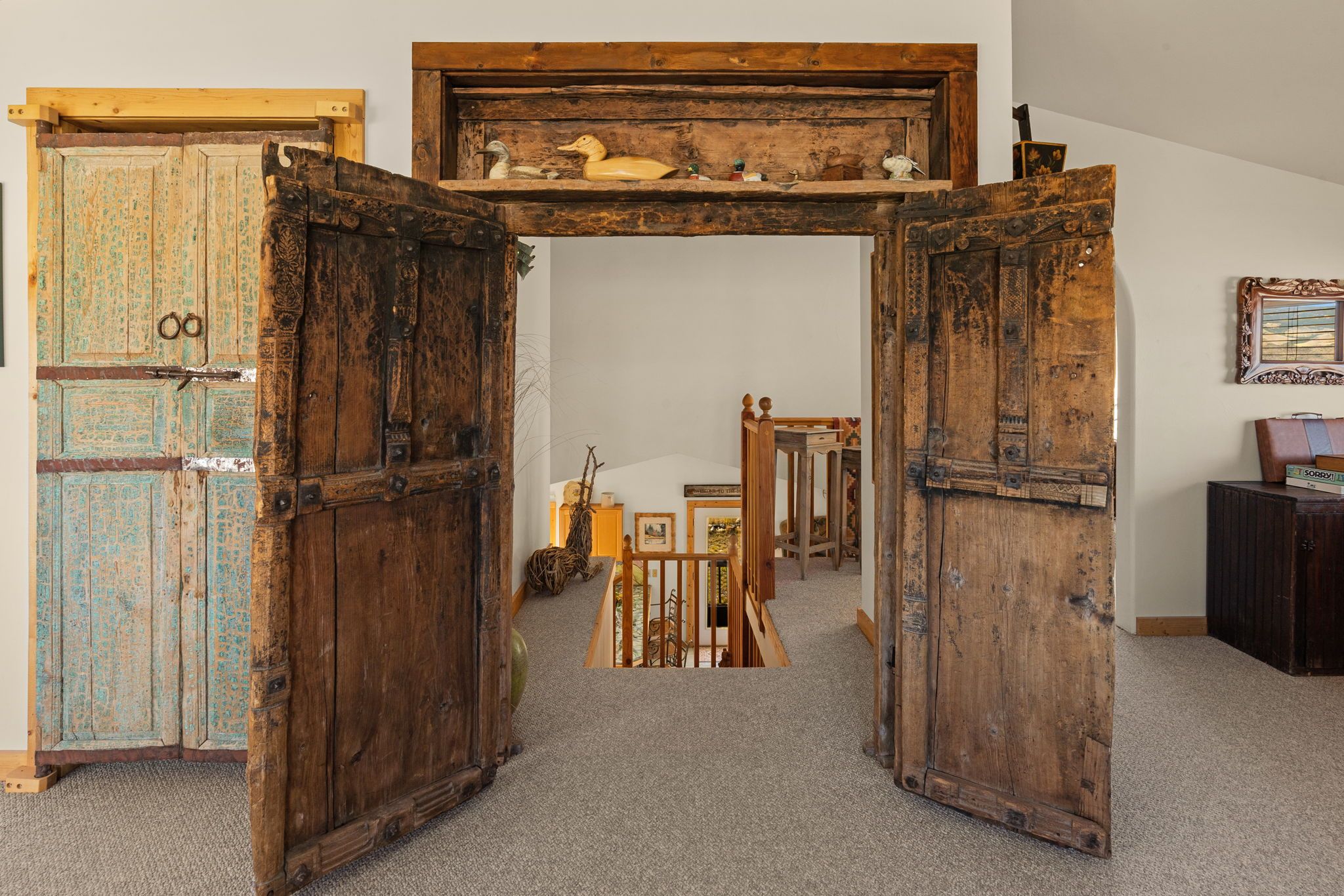 Un intérieur rustique avec des portes en bois, une petite table et un tableau encadré au mur.