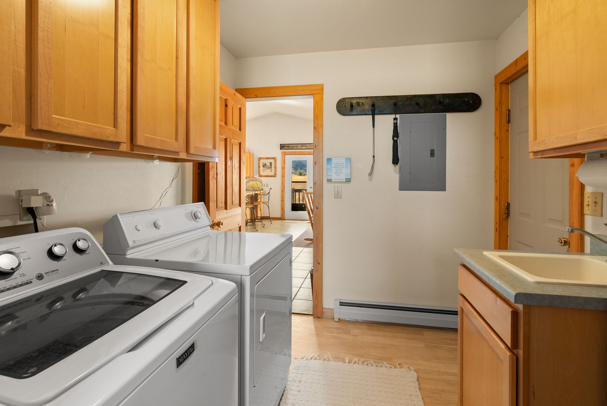 A kitchen with wooden cabinets, a stove, a dryer, and a small sink.