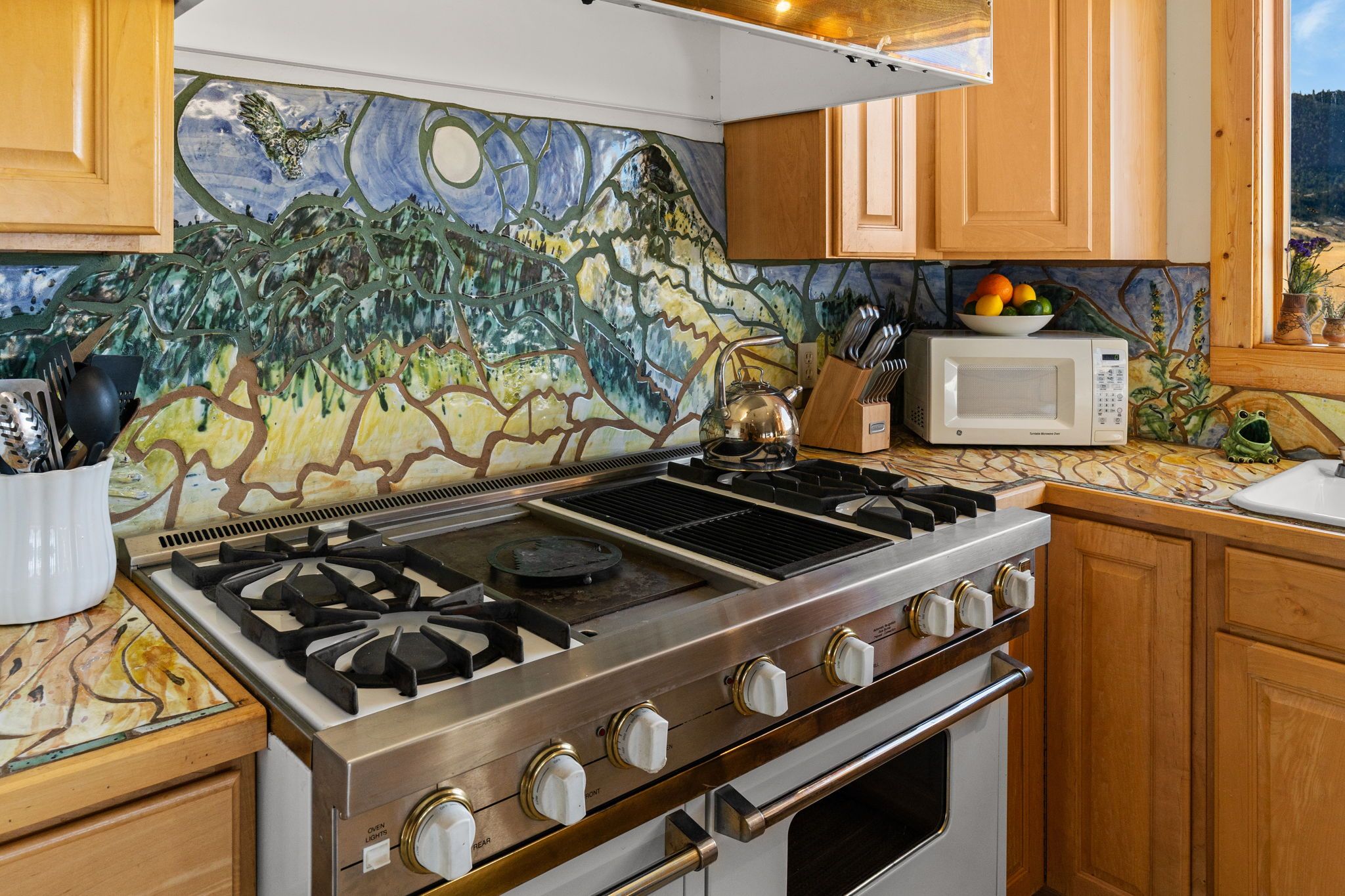 A kitchen with a gas stove, a microwave, and wooden cabinets.