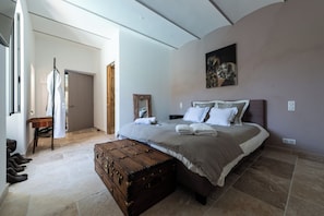 A bedroom with a large bed, a wooden chest, and a painting on the wall.