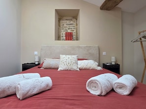 A hotel room with a large bed, a stone wall alcove, and a wooden ceiling beam. - Livia's House. An 18th-century village farmhouse between Uzès and Nîmes. (Sauzet)
