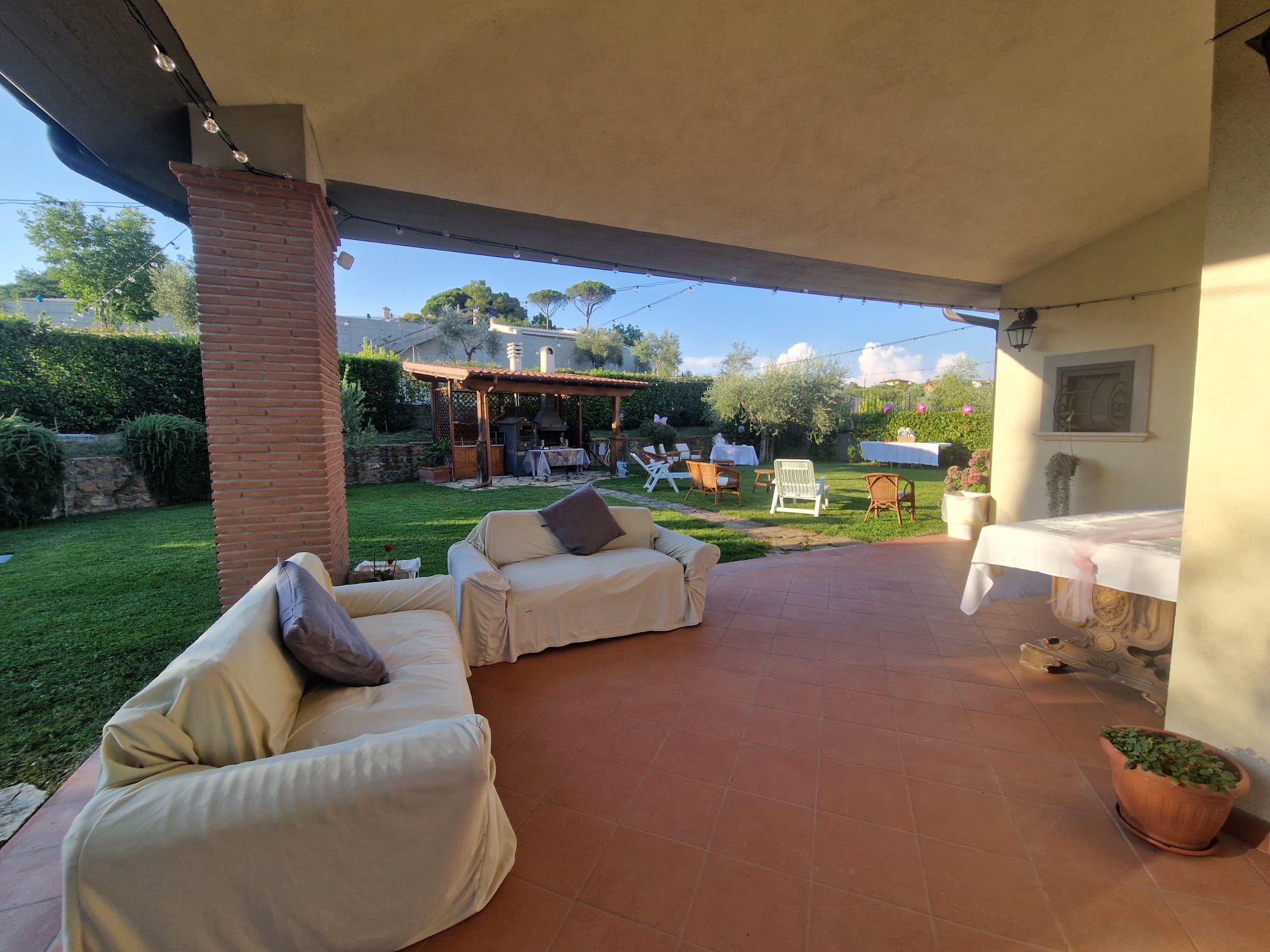Un espace extérieur aménagé en patio, doté d’un coin salon abrité, d’un barbecue et d’une table à manger pour les repas en plein air.