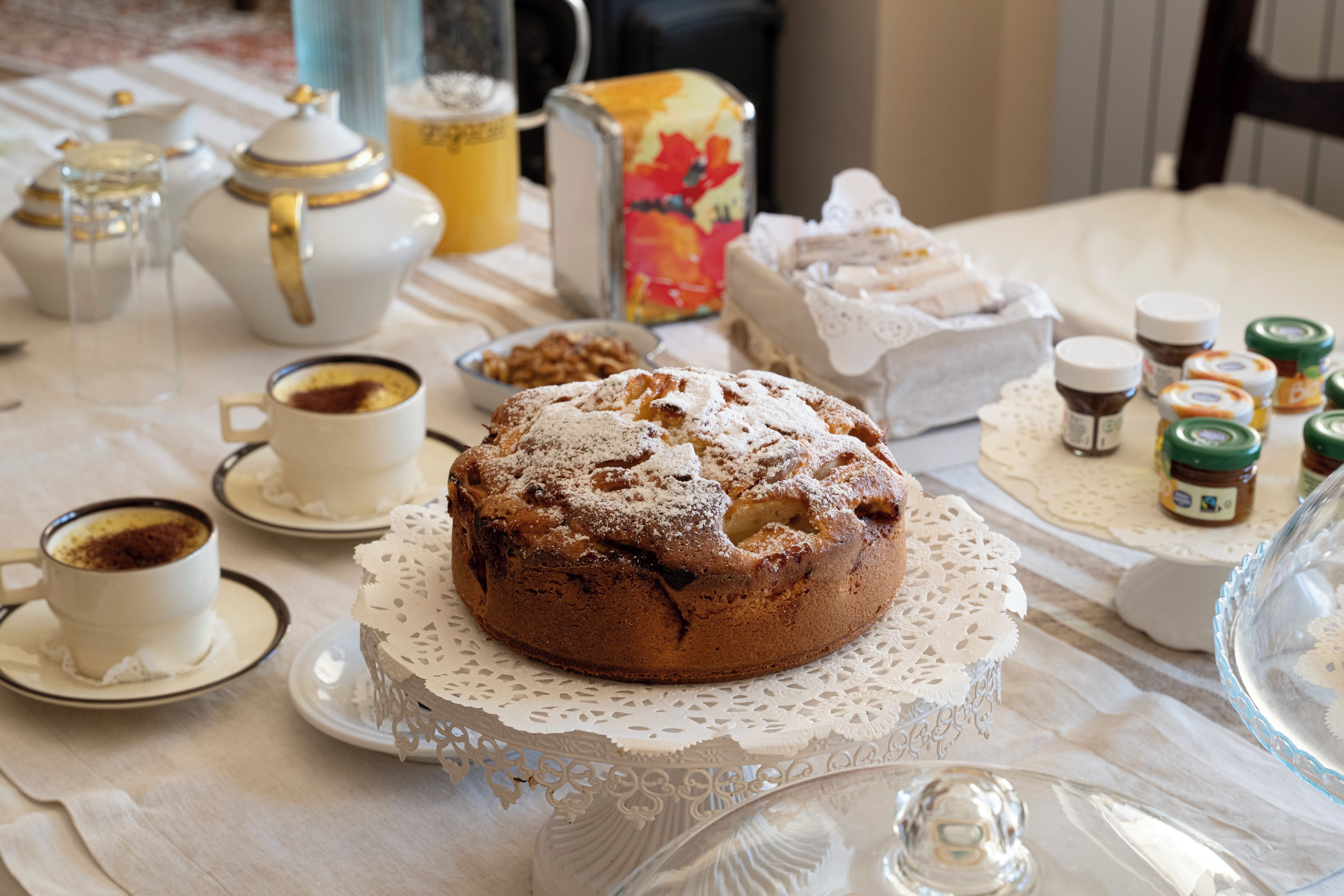 Ein Tisch mit Kuchen, Teekannen, Tassen und Gläsern mit Marmelade.