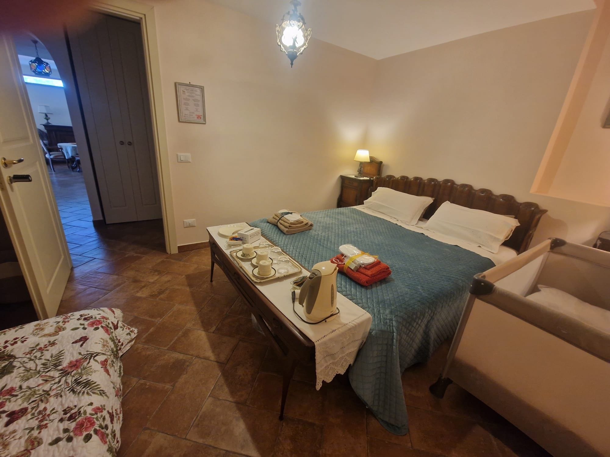 A hotel room with a bed, bedside table, lamp, and a chair.