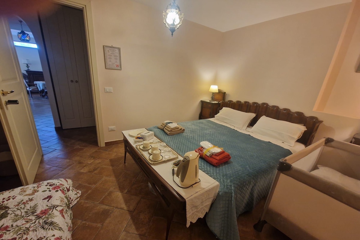 Una habitación de hotel con cama, mesita de noche, lámpara y una silla.