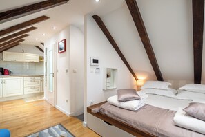 A bedroom with a loft-style ceiling, a bed with pillows, a bedside table, and a small bedside lamp. - D - beautiful studio in the heart of Split (Split)