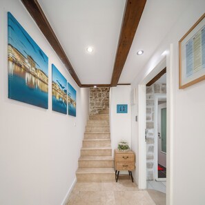 A staircase leading to a landing with a stone wall, a wooden cabinet, and three framed pictures on the wall. - D - beautiful studio in the heart of Split (Split)