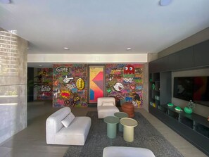A modern living room with graffiti-covered walls, a white sofa, a coffee table, and a TV on a black stand. - Residential Park by Domus Travels (San Joaquín)