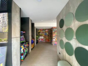 Een gang met speelautomaten, een muur met graffiti en een zithoek met ronde decoratie.