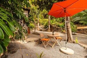 An outdoor seating area with a table and chairs, an orange umbrella, and a lantern. - Holiday Home 'Edele's House' with Mountain View, Private Terrace and Wi-Fi (Tabua)