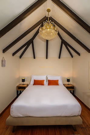 Ein Schlafzimmer mit einem großen Bett, zwei Nachttischen und einer Chandelier.