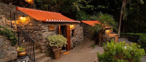 A stone building with a tiled roof, a wooden door, and a sign that reads 'COZINHA'.