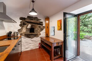 A kitchen with a stone wall, wooden cabinets, a built-in oven, and a sliding glass door to the outdoors. - Holiday Home 'Kyra's House' with Wi-Fi (Tabua)