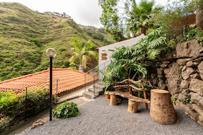 A terraced garden with a stone wall, a wooden bench, and a staircase leading to a building with a red-tiled roof. - Holiday Home 'Kyra's House' with Wi-Fi (Tabua)
