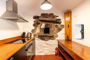 A kitchen with a stone oven, wooden cabinets, and a modern stove. - Holiday Home 'Kyra's House' with Wi-Fi (Tabua)
