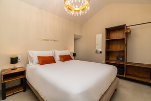 A hotel room with a large bed, a wooden nightstand, a bedside table with a lamp, a wardrobe, and a chandelier. - Holiday Home 'Kyra's House' with Wi-Fi (Tabua)