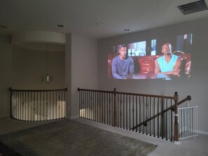 A room with a staircase, a television screen, and a railing. - Katy Retreat - 5 Bed -Pergola- 5 min to Katy Mills (Katy)