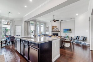 A spacious kitchen with a large island, a dining area with a table and chairs, and a living area with a sofa and a TV. - Katy Retreat - 5 Bed -Pergola- 5 min to Katy Mills (Katy)