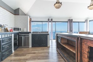 Eine moderne Küche mit einer großen Kochinsel, Edelstahlgeräten und Meerblick.