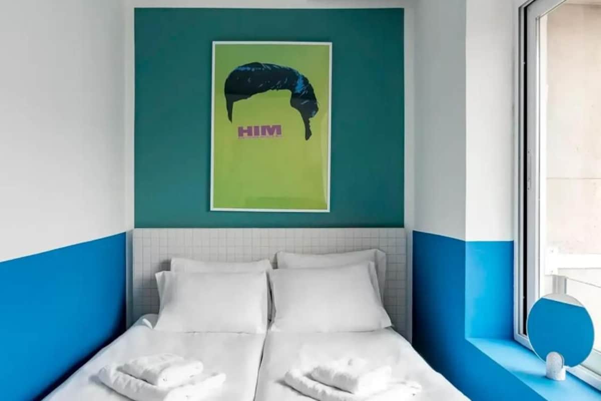 A hotel room with a bed, a window, and a wall-mounted artwork.