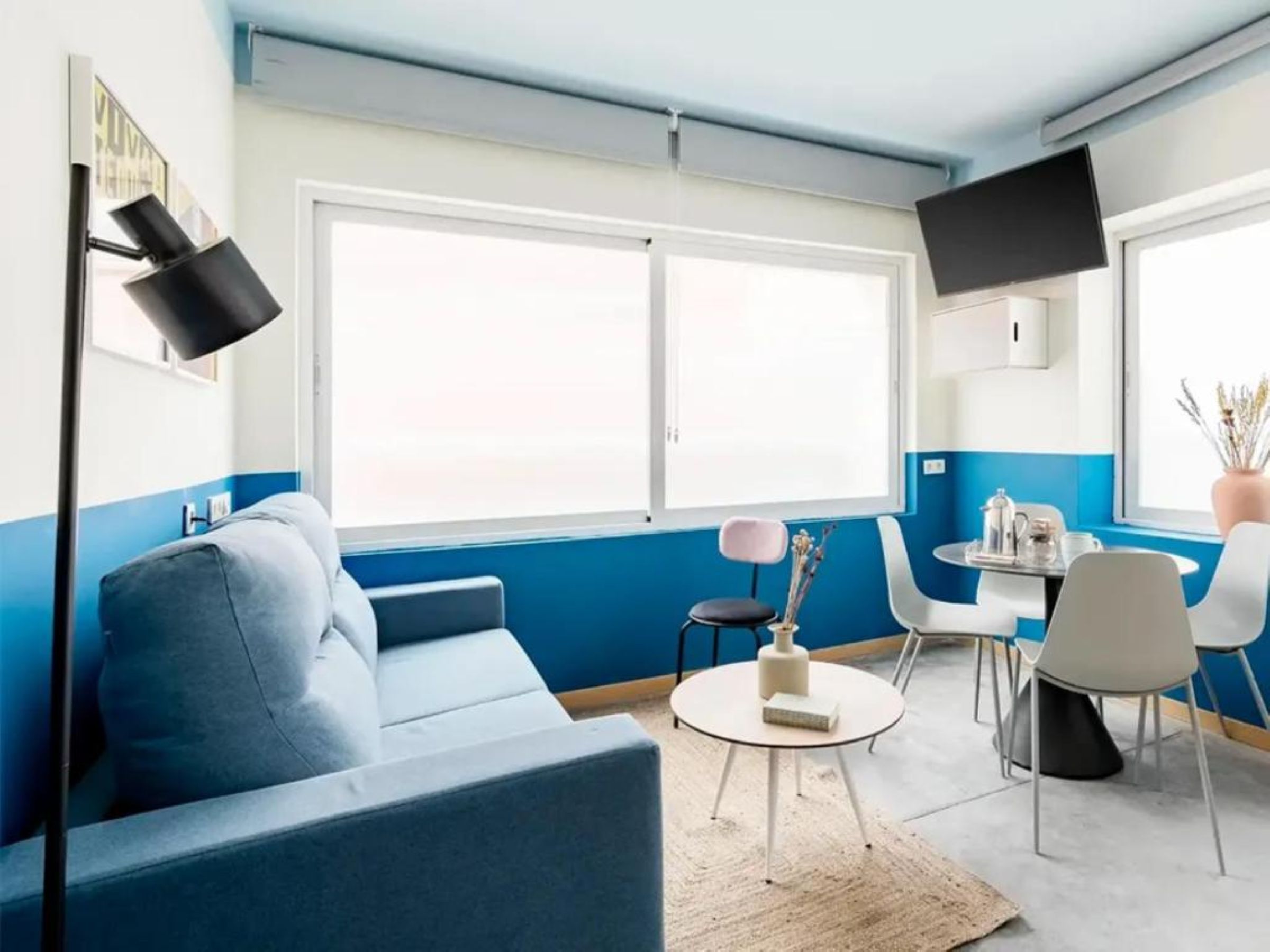 Un salon moderne avec un canapé, une petite table, un fauteuil et un téléviseur fixé au mur.