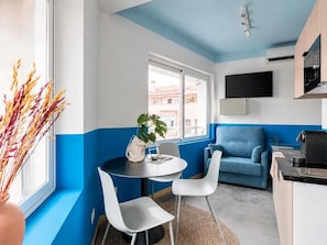 A modern kitchen with a blue accent wall, a dining area with a round table and white chairs, and a blue sofa.