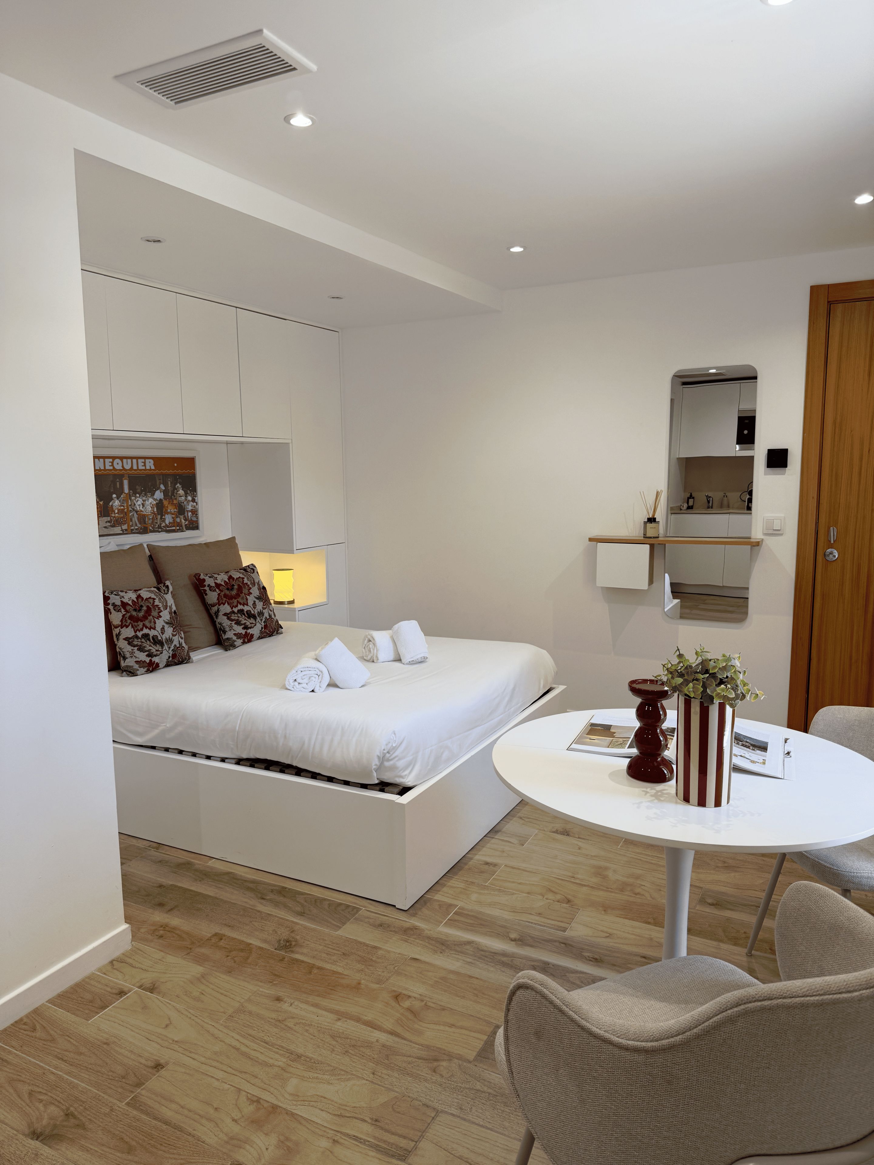 A modern bedroom with a built-in bed, a small round table, and a mirror above the bed.