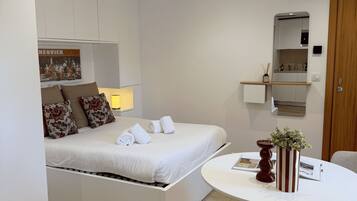 A modern bedroom with a built-in bed, a small round table, and a mirror above the bed.