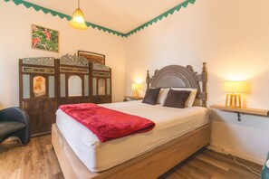 A bedroom with a bed, bedside lamps, a wooden headboard, a decorative wall piece, and a chair. - Casa Hui Nosso Jardim by Atlantic Holiday (Calheta)