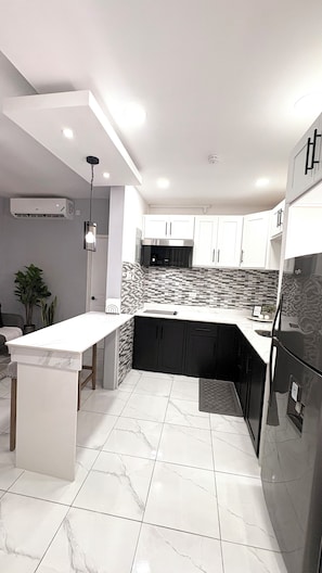 A modern kitchen with white cabinetry, a black countertop island, and a tiled backsplash. - Modern 1 Bedroom Apartment Centrally Located in the heart of Kingston (Kingston)