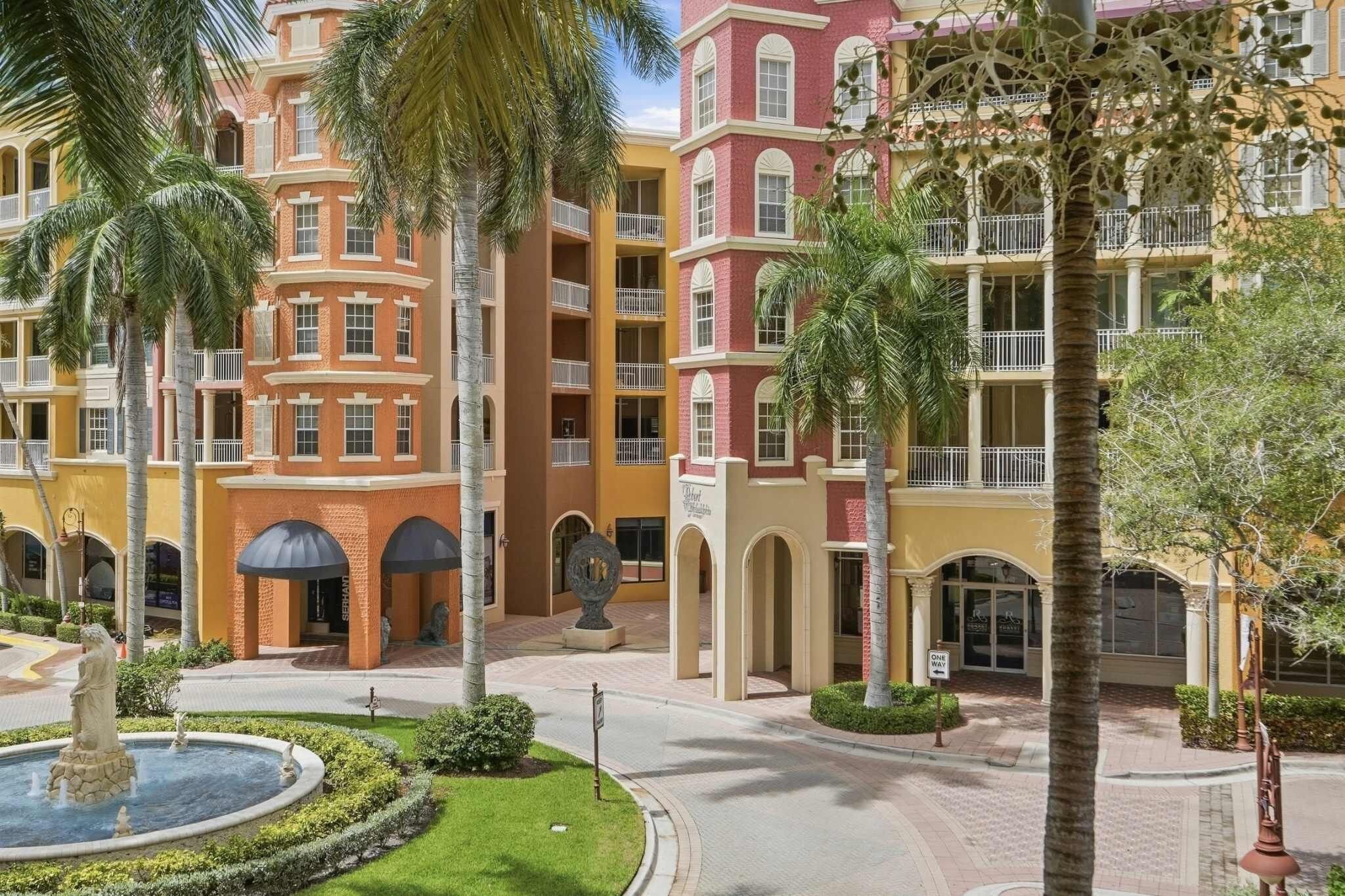 Un hôtel à plusieurs étages doté d’une cour intérieure, de palmiers et d’une fontaine.