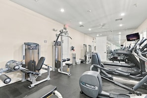 A gym with various exercise equipment including treadmills, a bench press, and a cable machine. - Bayfront Naples – Downtown Waterfront Living with Rooftop Pool & Restaurants (Naples)