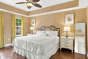 A bedroom with a large bed, two bedside tables with lamps, a ceiling fan, and artwork on the walls. - Bayfront Naples – Downtown Waterfront Living with Rooftop Pool & Restaurants (Naples)